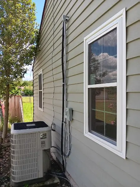 Finished window on a beige house beside an AC unit and routed electrical wiring