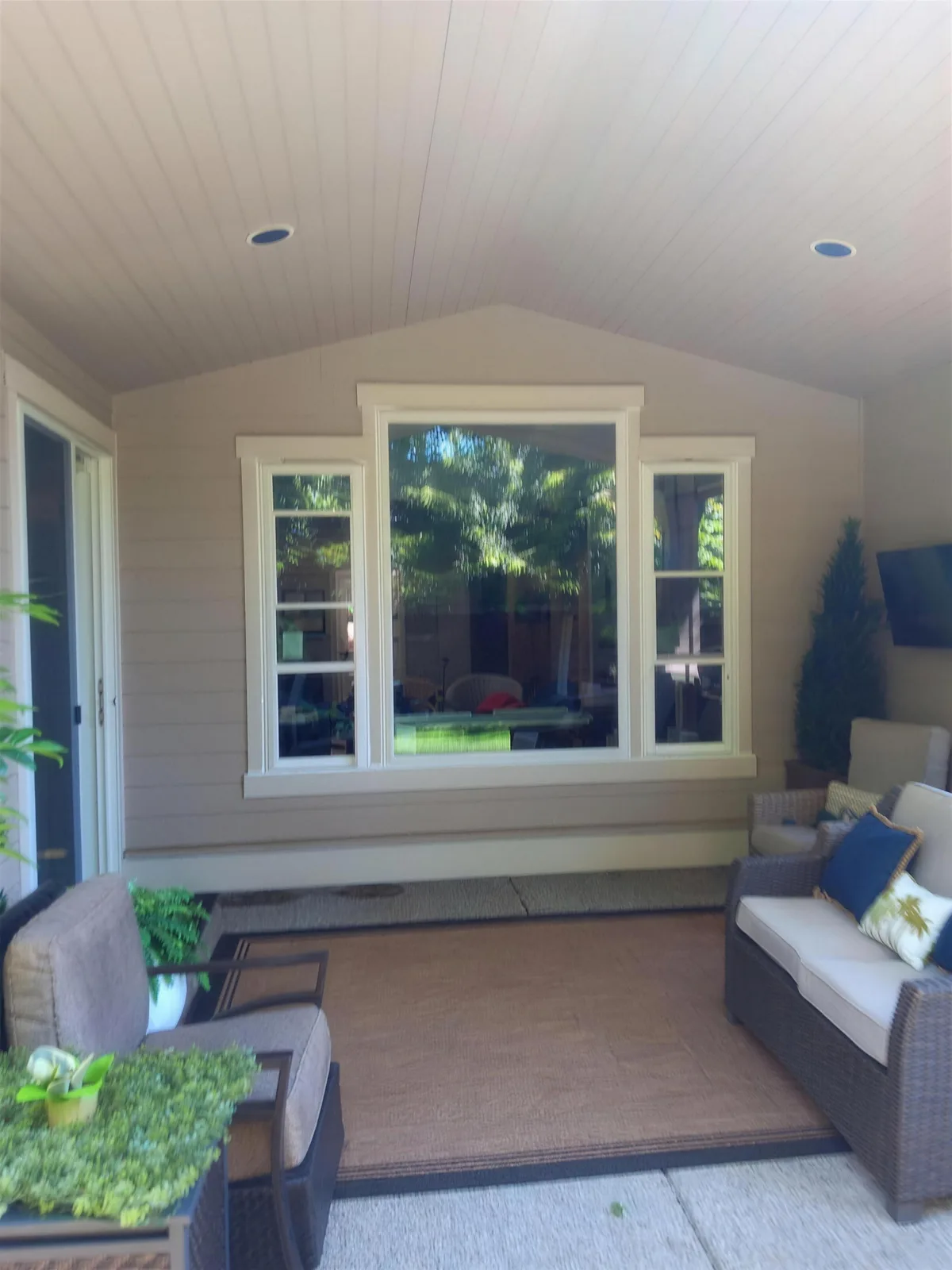 Bright sitting room with a large window between two narrow windows and a vaulted ceiling