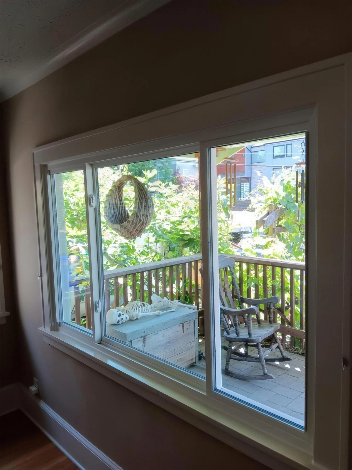 White-trimmed window seen from inside a room overlooking a covered deck and green trees