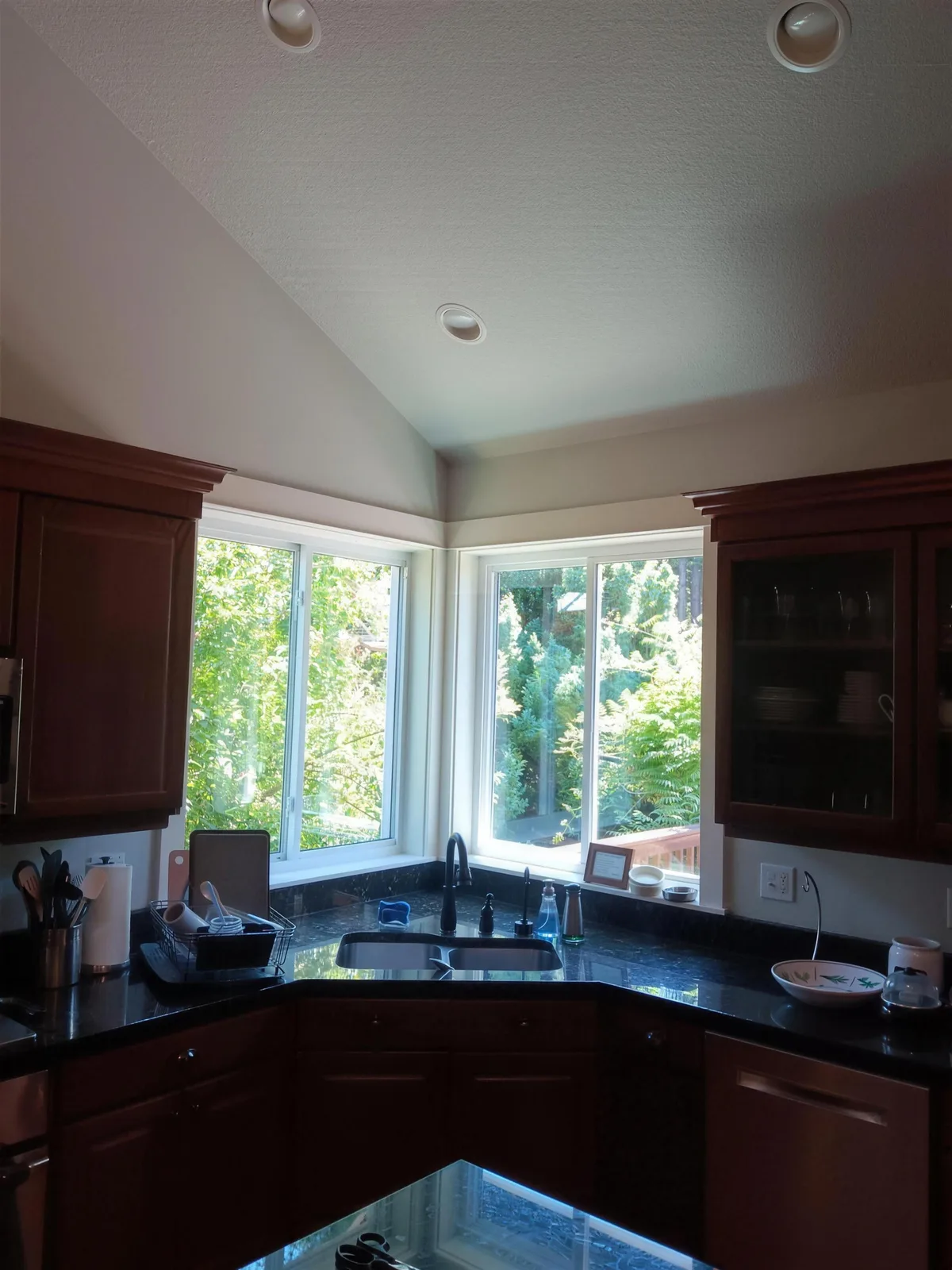 White corner windows above a kitchen sink and dark wood cabinets