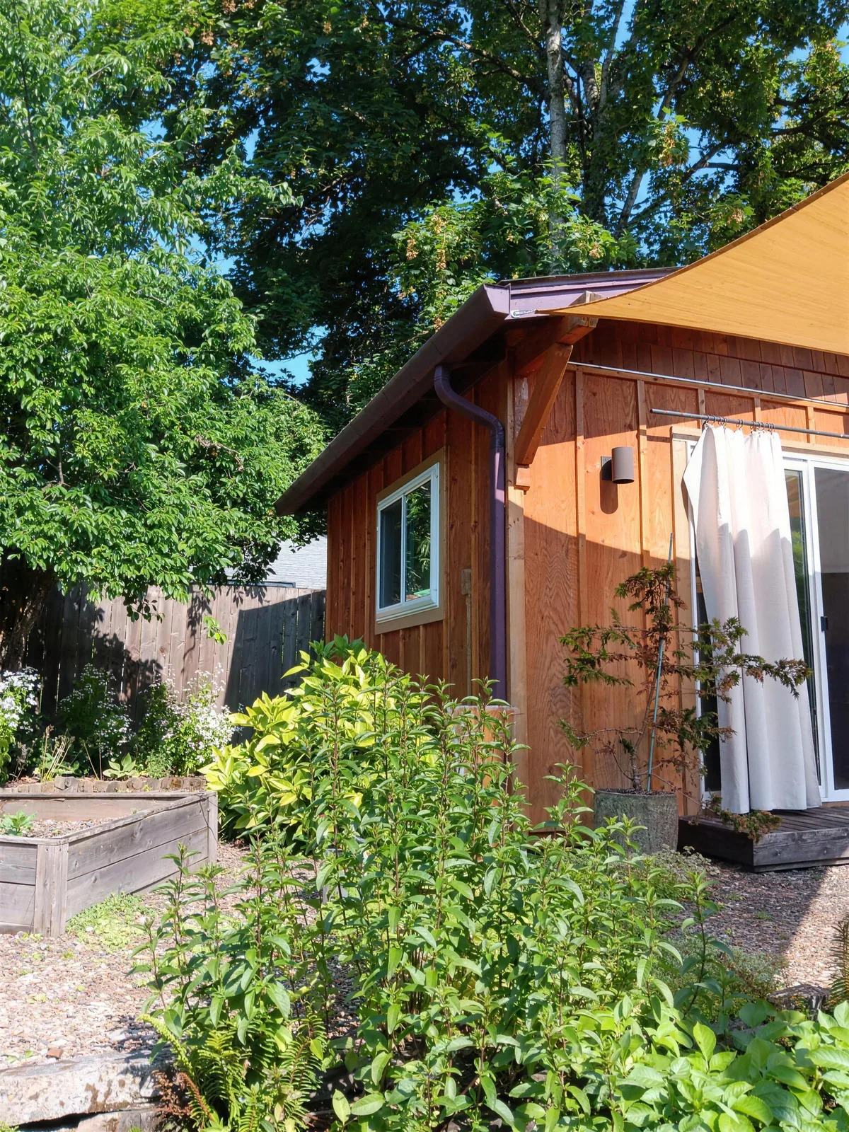 White-trimmed windows along a wood-sided home beside a green garden