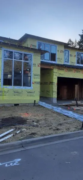 Windows set and flashed in a sheathed two-story new build, taped seams, before siding
