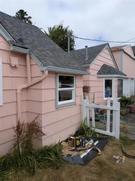 Pink bungalow with new white double-hung windows after replacement