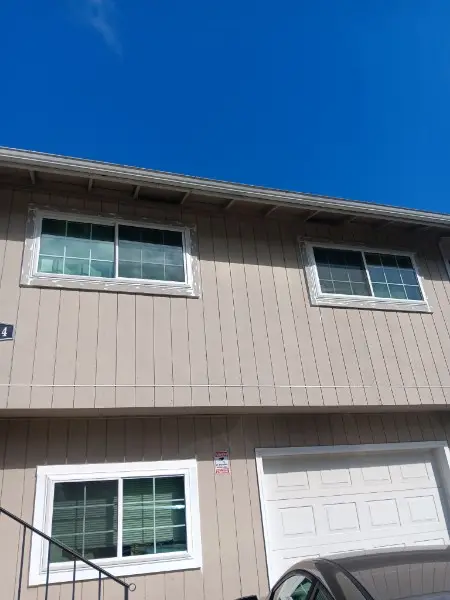 Tan two-story house with new white sliders above a garage