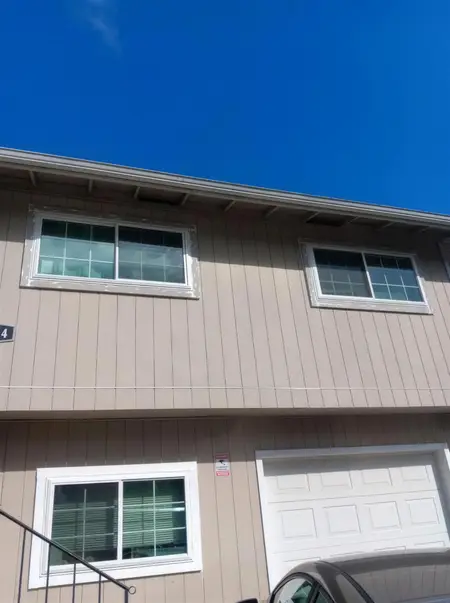 Tan two-story house with new white sliders above a garage