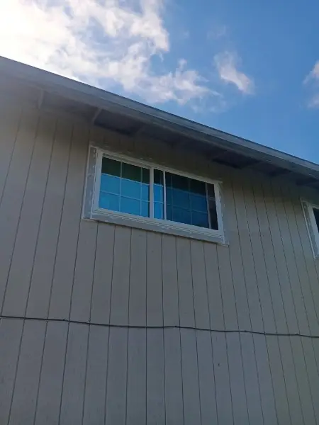 Close view of an upper-story white slider on tan vertical siding