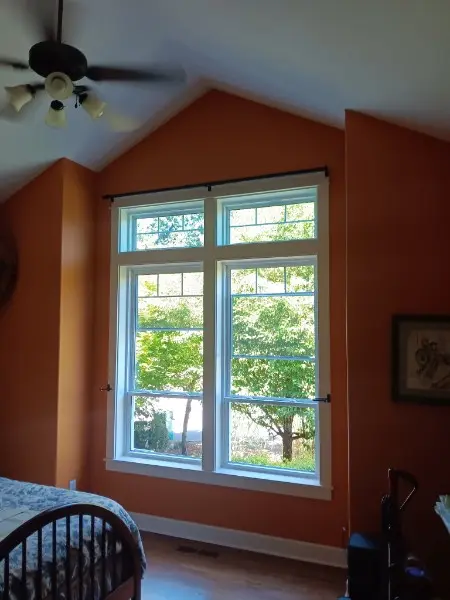 Pair of white double-hung windows with grids in a vaulted bedroom